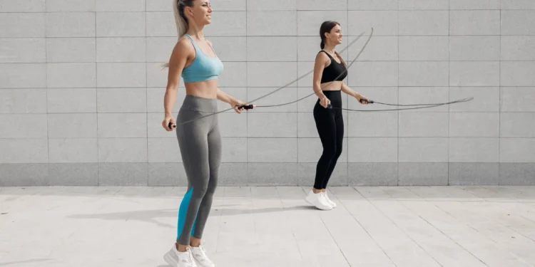 Duas mulheres praticando exercício de pular corda ao ar livre, destacando benefícios para o condicionamento físico.