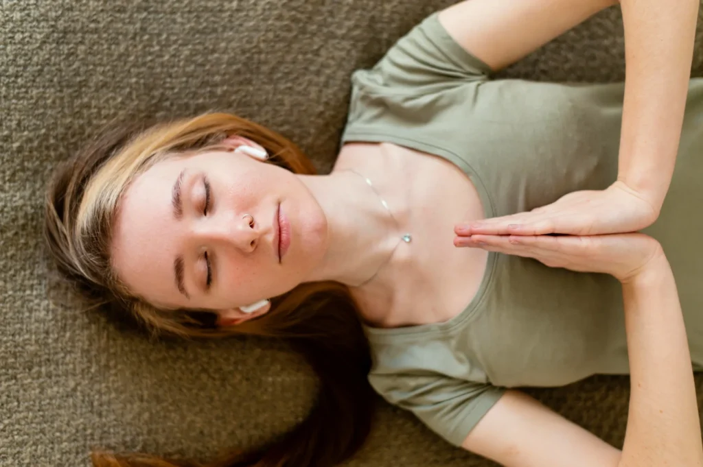 Mulher jovem de olhos fechados, praticando meditação e respiração para relaxar em casa.