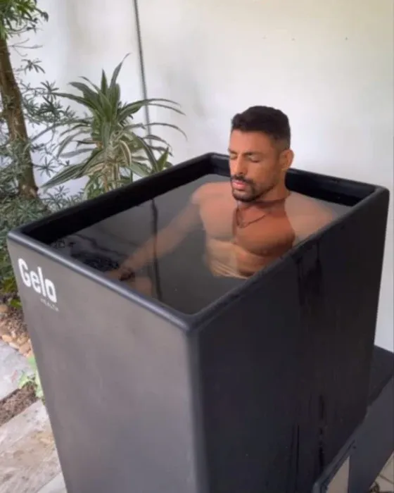 Ator em banho de gelo após treino, imerso em uma banheira preta.