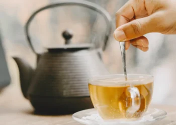 Chá de oliveira sendo preparado com colher, ideal para eliminar gordura abdominal