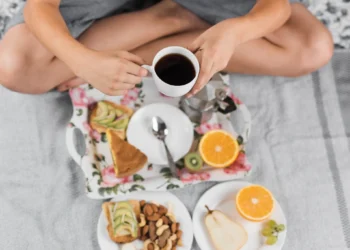 Café da manhã com frutas, castanhas, pão com abacate e xícara de café