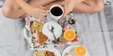Café da manhã com frutas, castanhas, pão com abacate e xícara de café