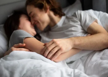 Casal se abraçando com carinho na cama, demonstrando afeto e conexão íntima