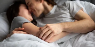Casal se abraçando com carinho na cama, demonstrando afeto e conexão íntima