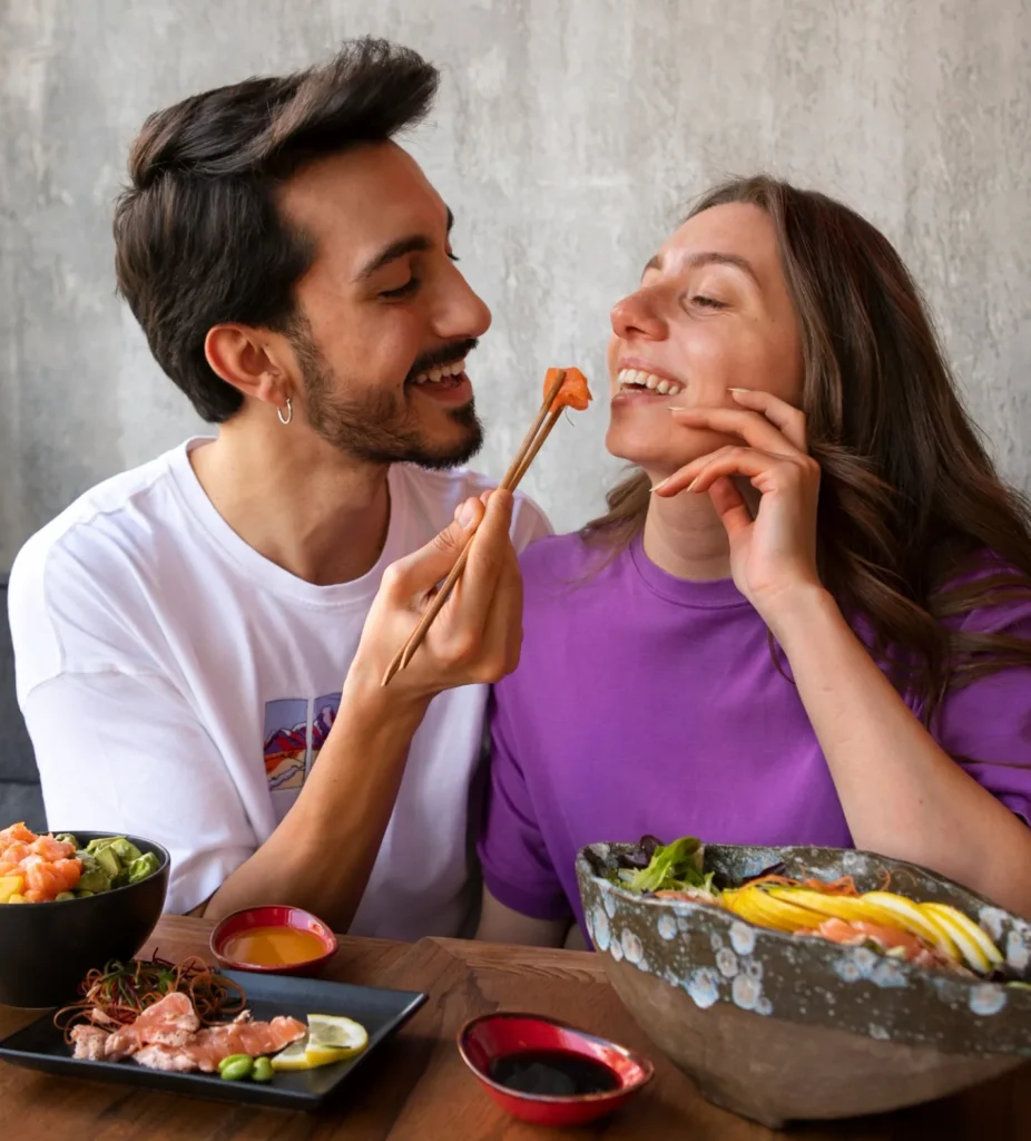 Casal sorrindo enquanto compartilha um prato com salmão em um restaurante