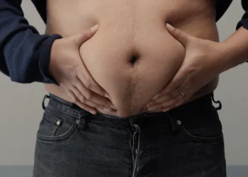 Homem segurando a barriga para ilustrar a luta contra a gordura abdominal