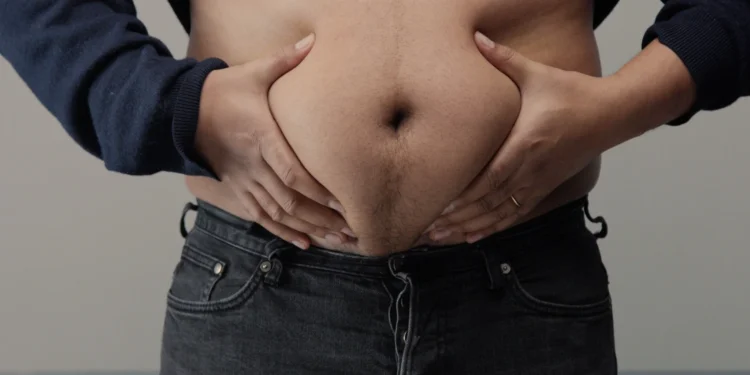 Homem segurando a barriga para ilustrar a luta contra a gordura abdominal