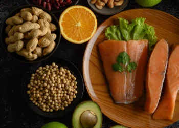 Prato com salmão, legumes, frutas e nozes, exemplificando alimentos ricos em nutrientes para uma dieta mediterrânea.