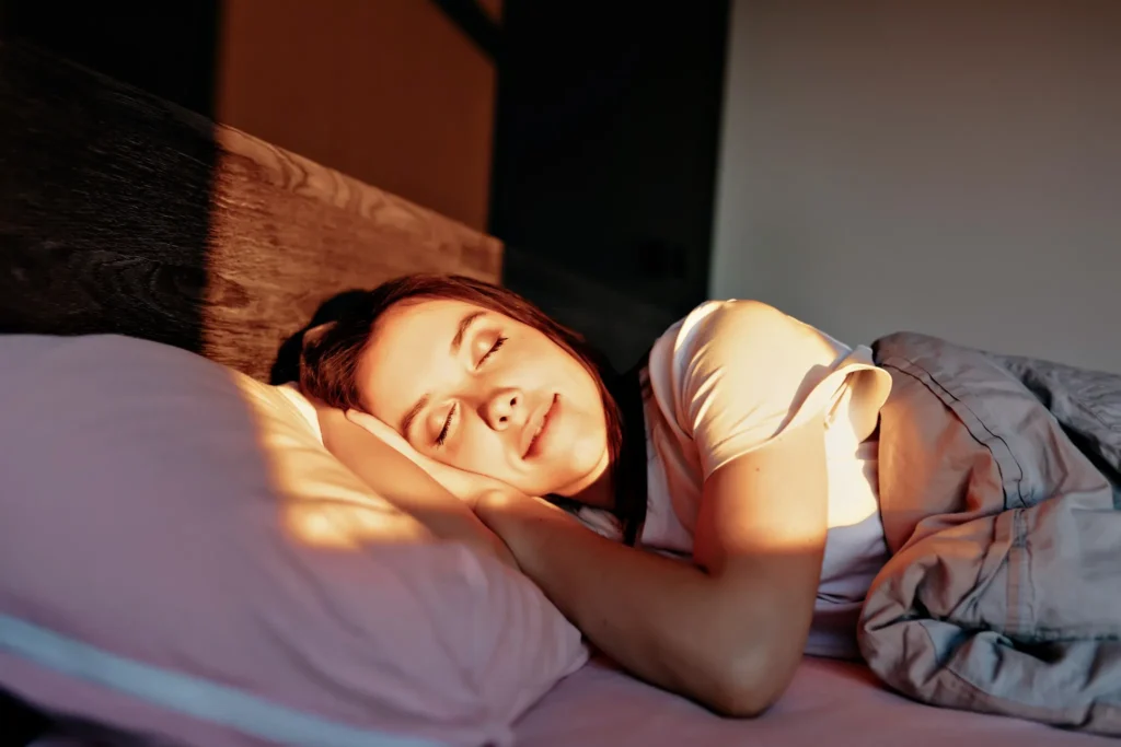 Mulher dormindo tranquilamente, aproveitando um sono restaurador ao amanhecer.