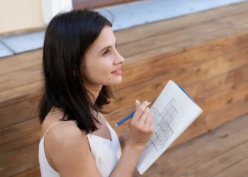 Mulher concentrada resolvendo um jogo de sudoku, exercitando o cérebro para melhorar o desempenho mental durante o dia.