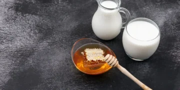 Imagem mostrando leite com mel, um remédio natural, em um fundo preto, destacando os benefícios para a saúde