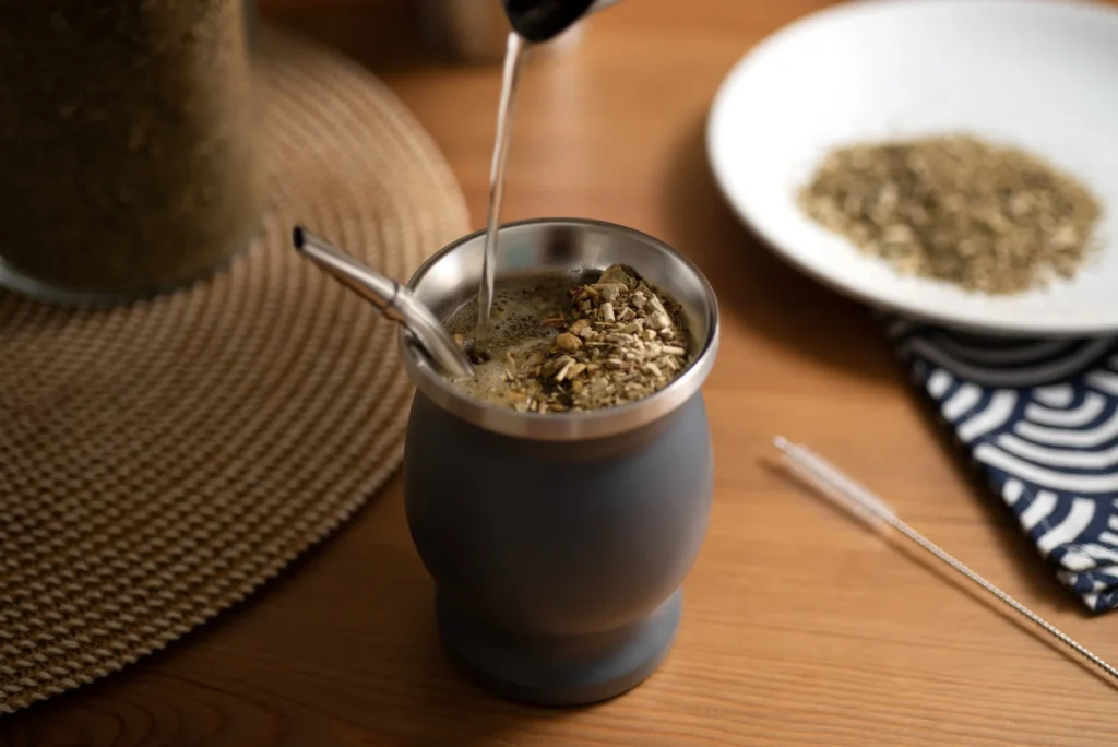Preparação de chimarrão com erva-mate sendo servido em um recipiente tradicional.