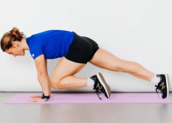 Mulher executando mountain climbers, um exercício de alta intensidade, com foco na queima de gordura localizada, em um tapete de yoga lavanda.