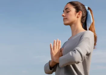 Mulher praticando respiração ao ar livre com expressão de tranquilidade