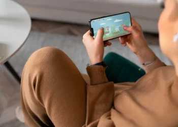 Mulher jogando em celular, imagem ilustrativa de app de treinamento cognitivo.