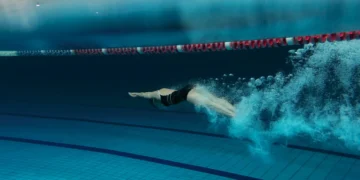 Pessoa realizando mergulho em piscina durante treino de natação.