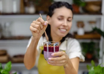 Mulher segurando copo com pudim de chia, frutas vermelhas e granola