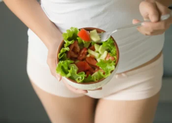Mulher segurando uma tigela de salada com tomate e pepino, uma opção saudável para quem sofre de candidíase.
