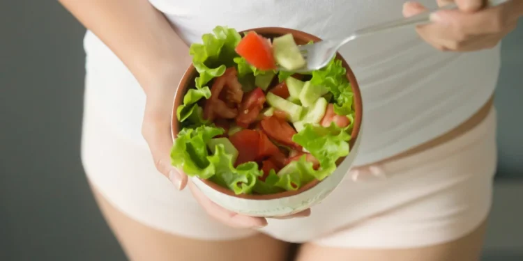 Mulher segurando uma tigela de salada com tomate e pepino, uma opção saudável para quem sofre de candidíase.
