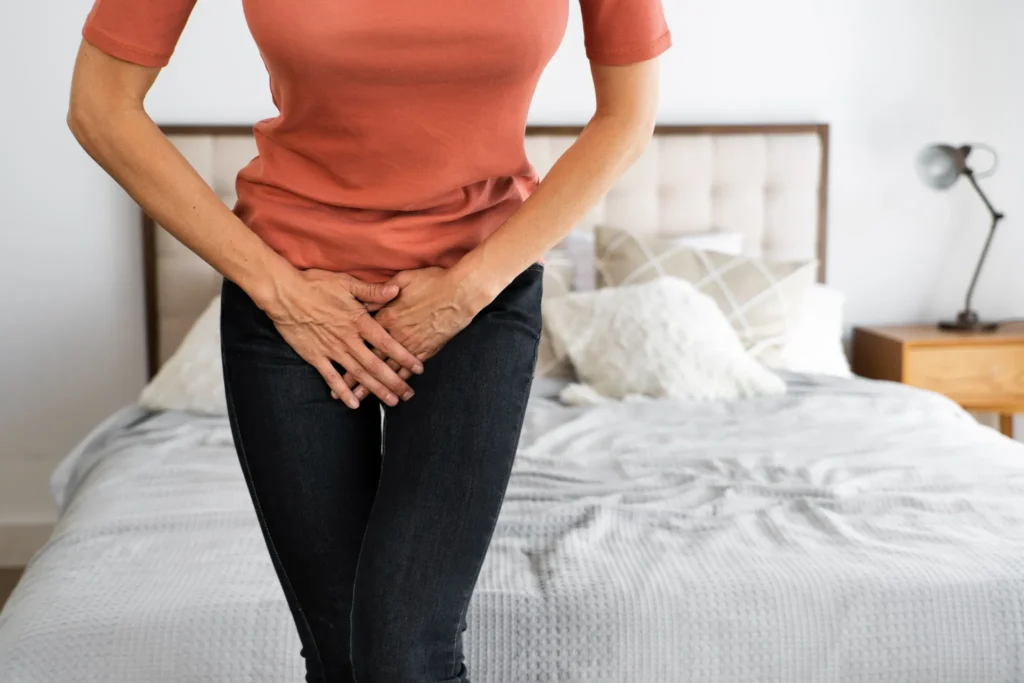 Mulher com dor abdominal, indicando possíveis sintomas de candidíase, em ambiente doméstico.