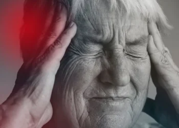 Idosa com expressão de dor e desconforto, ilustrando sintomas iniciais de Alzheimer.