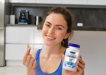 Mulher sorrindo segura cápsula e pote do suplemento natural Memorizen para memória