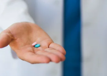 Comprimidos coloridos nas mãos de um profissional de saúde, ilustrando o uso de tadalafila em tratamentos e academias.