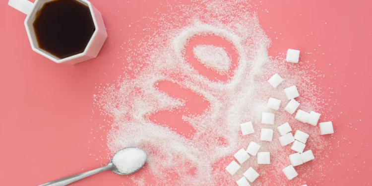 Cubos de açúcar e açúcar espalhado sobre uma superfície rosa, simbolizando uma reflexão sobre o impacto do açúcar no corpo.