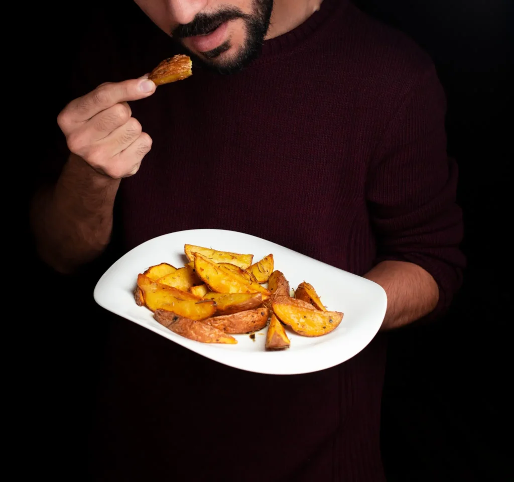 Homem degustando batatas cozidas em prato branco