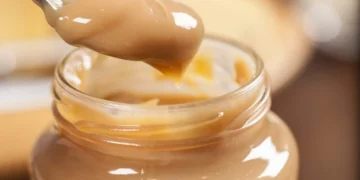 Doce de leite servido em pote com uma colher, ilustrando o uso como pré-treino.