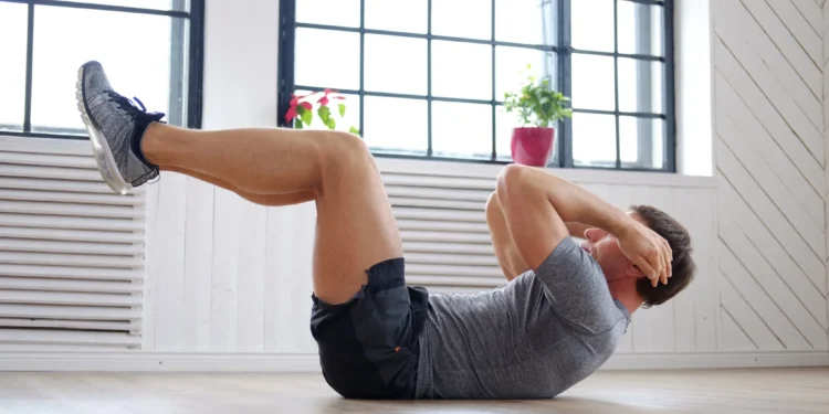 Homem realizando exercício abdominal em casa, ajudando a reduzir a barriguinha com atividade física.