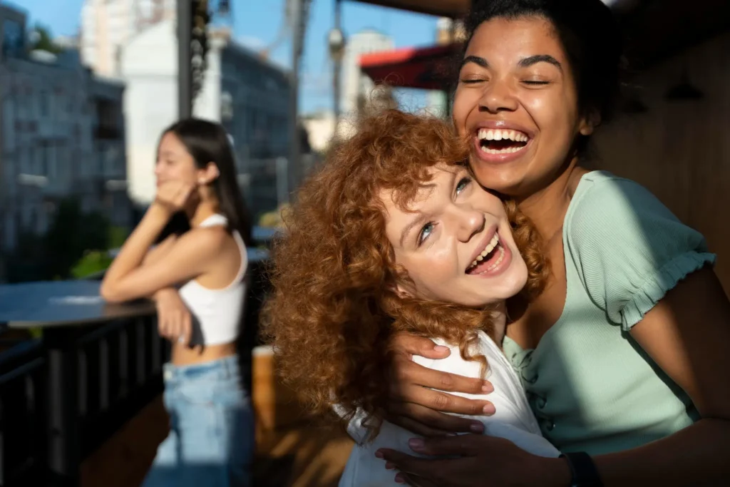 Grupo de amigos sorrindo ao ar livre, compartilhando momentos felizes juntos, representando a importância da socialização para o bem-estar.
