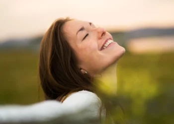 Mulher sorridente aproveitando um momento de felicidade ao ar livre, ativando o hormônio da felicidade com atitudes simples.