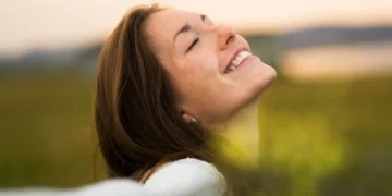 Mulher sorridente aproveitando um momento de felicidade ao ar livre, ativando o hormônio da felicidade com atitudes simples.