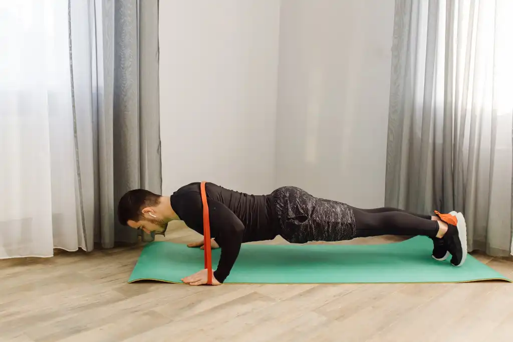 Homem realizando flexão de braço com faixas de resistência.