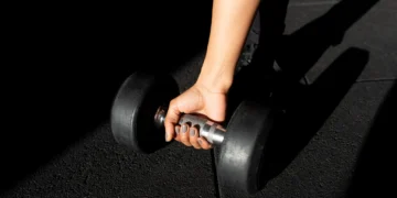 Pessoa segurando haltere durante exercício para evitar lesões e melhorar a progressão de carga no treino