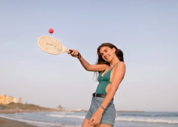 Mulher se divertindo jogando Beach Tennis na praia, usando raquete e bola