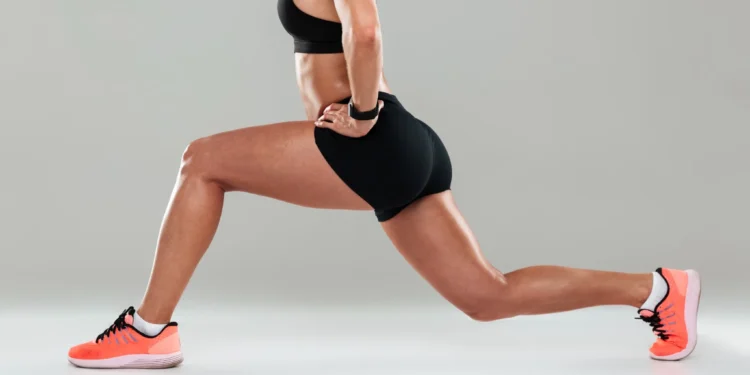 Mulher jovem em treino, fazendo exercício de agachamento para tonificar coxas.