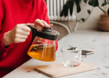 Pessoa preparando chá para emagrecer, destacando o processo de infusão em uma cozinha aconchegante