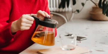 Pessoa preparando chá para emagrecer, destacando o processo de infusão em uma cozinha aconchegante
