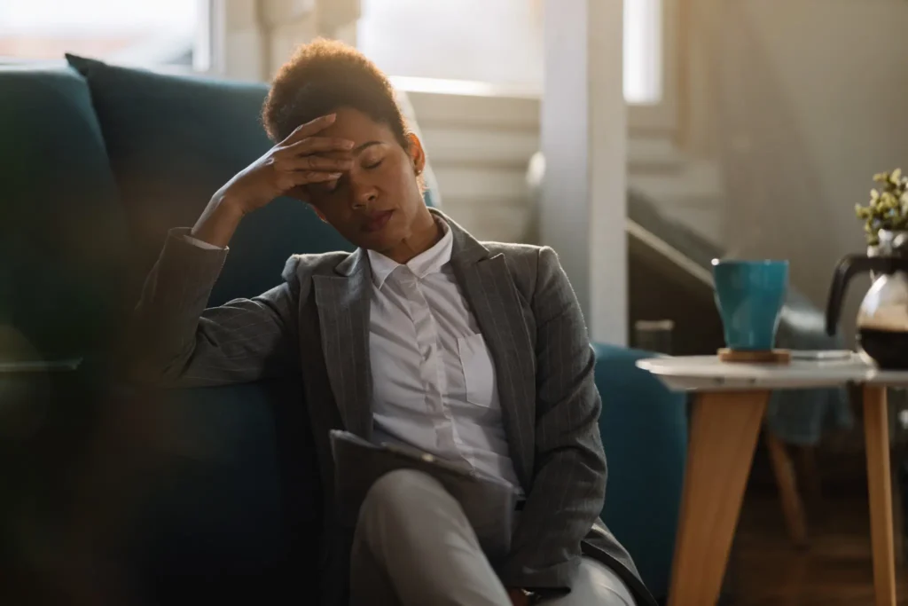 Empresária afro-americana demonstrando sinais de exaustão emocional enquanto trabalha em casa.