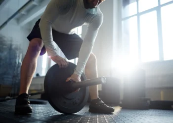 Homem levantando peso para treino de força muscular no ginásio