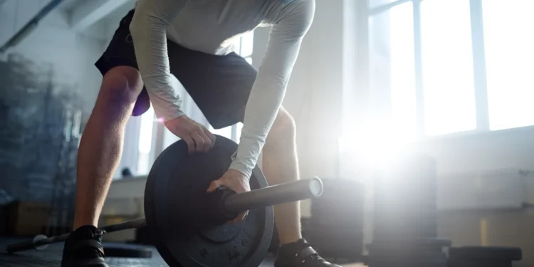 Homem levantando peso para treino de força muscular no ginásio