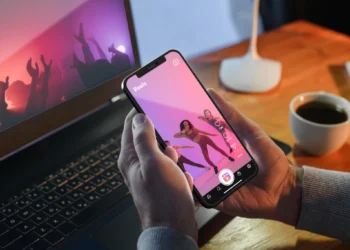 Pessoa assistindo a um vídeo acelerado no celular, com luzes coloridas no fundo.