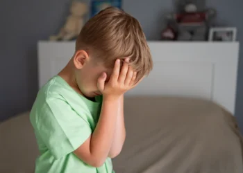 Criança com expressão de tristeza cobrindo o rosto, possível sinal de ansiedade infantil