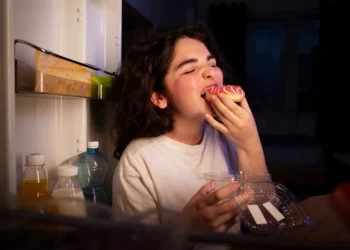 Mulher com fome comendo durante a madrugada.