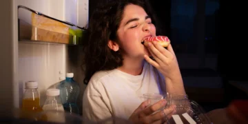 Mulher com fome comendo durante a madrugada.