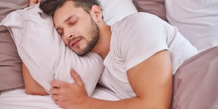 Homem dormindo profundamente abraçado ao travesseiro, representando sintomas comuns do ronco.