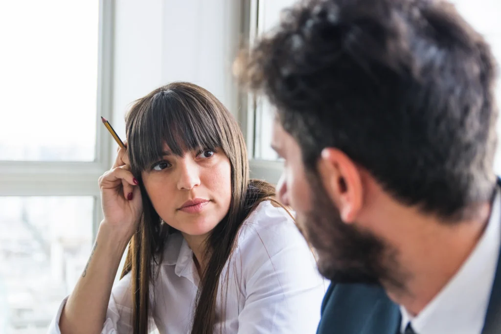 Mulher observa atentamente homem em uma conversa, com foco no contato visual que transmite interesse.