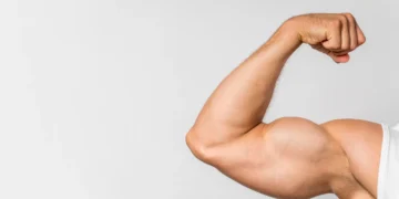 Braço musculoso de um homem em pose de flexão, destacando a definição muscular.